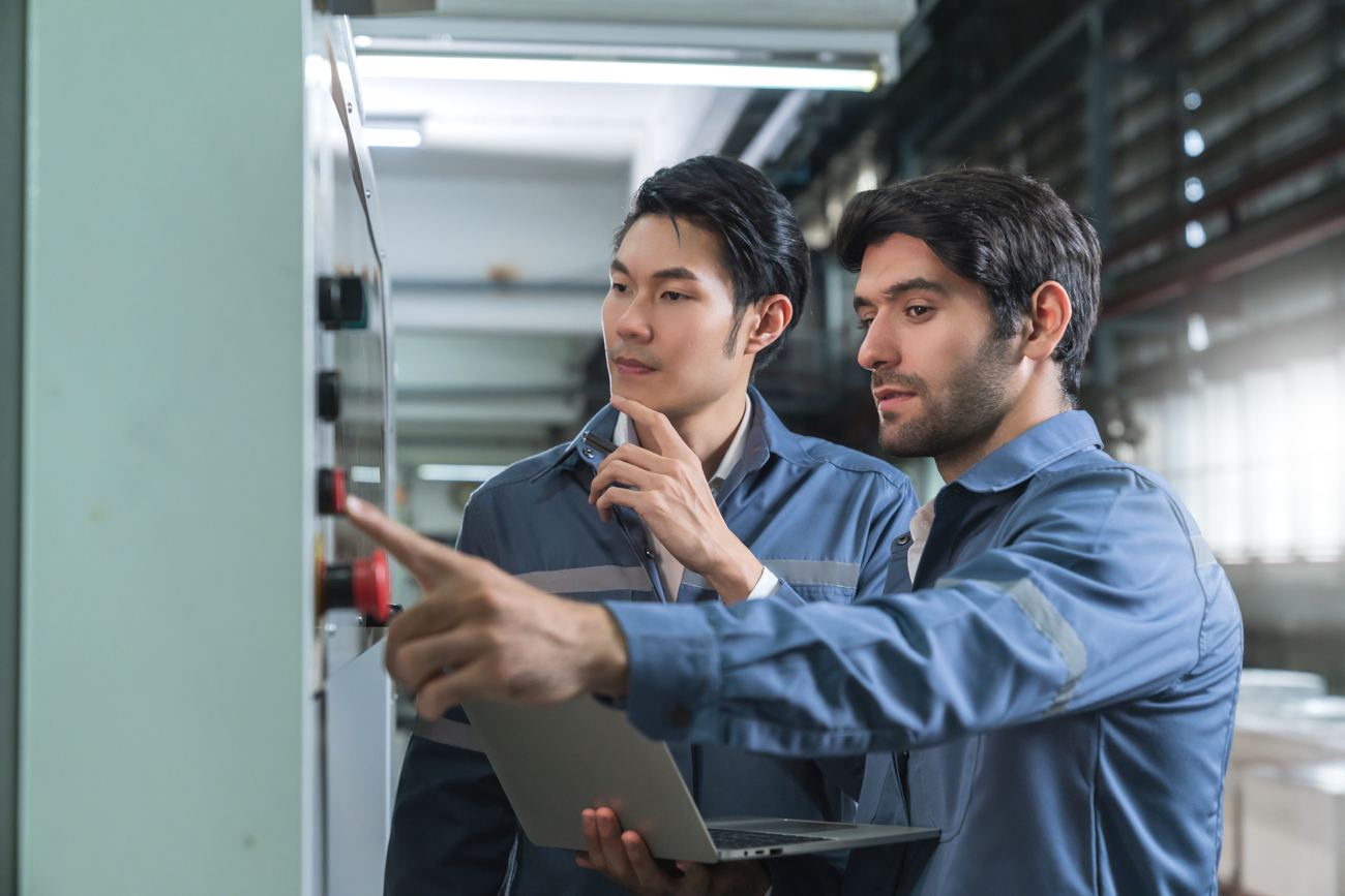 Two engineers consulting at a machine control panel